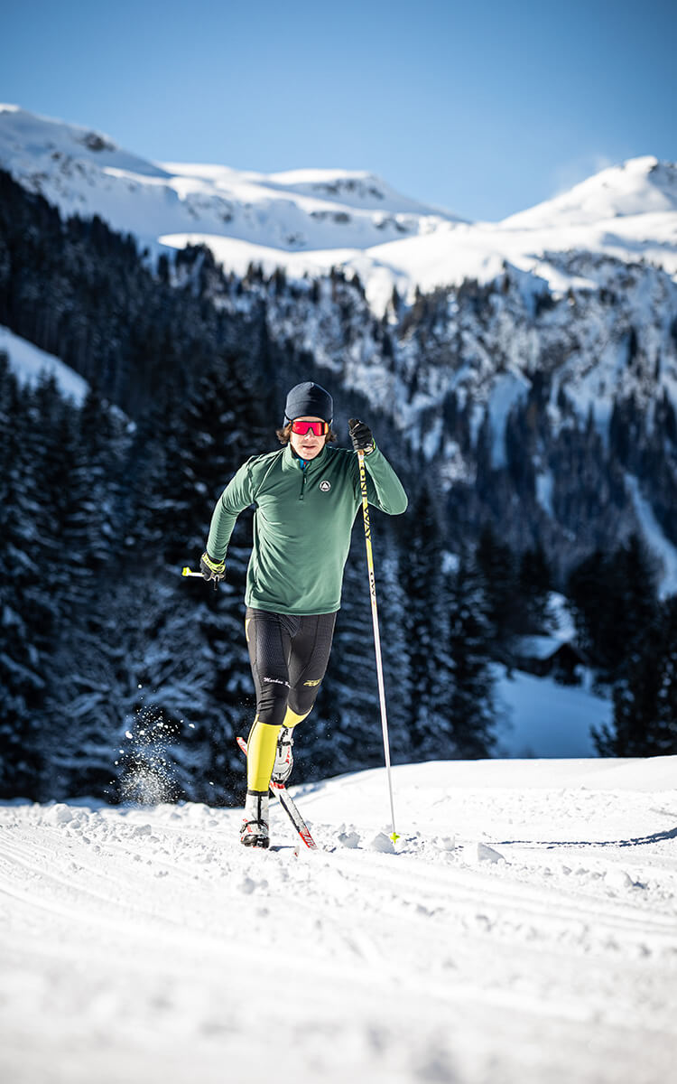 Mann beim Langlauf mit winterlichem Berggipfel im Hintergrund